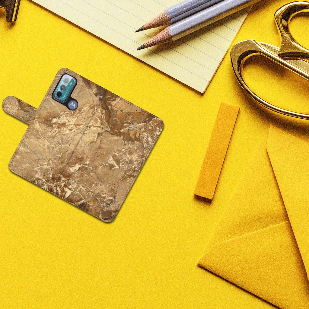 Motorola Moto G60 Bookcase Marmer Creme op een gele achtergrond met schoolbenodigdheden.