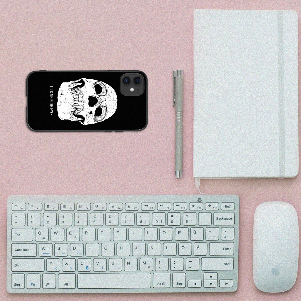 Telefoonhoesje iPhone 11 Skull Eyes op een bureau met toetsenbord en notitieboek.