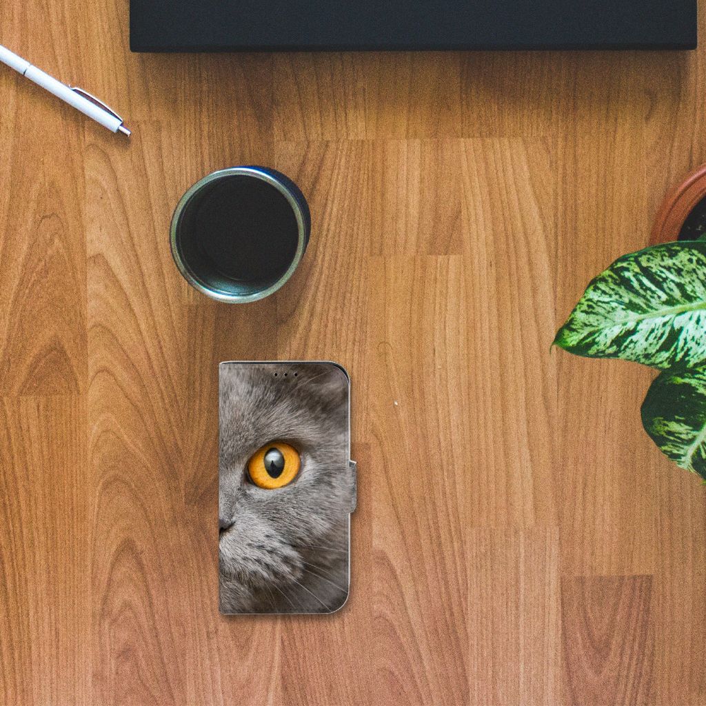 Telefoonhoesje met Pasjes iPhone 13 Mini Britse Korthaar op een houten tafel met een plant en een kopje koffie.
