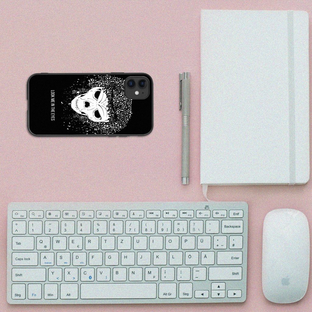 Telefoonhoesje iPhone 11 Skull Hair met skull design op een bureau met toetsenbord en notitieboek.