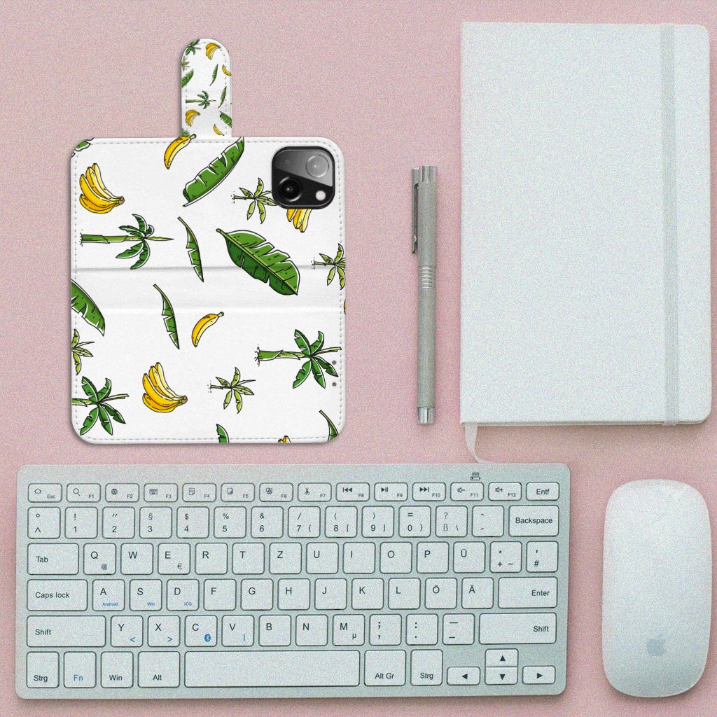 iPhone 13 Mini Hoesje Banana Tree met vrolijk bananen- en palmboomdesign naast bureauaccessoires.