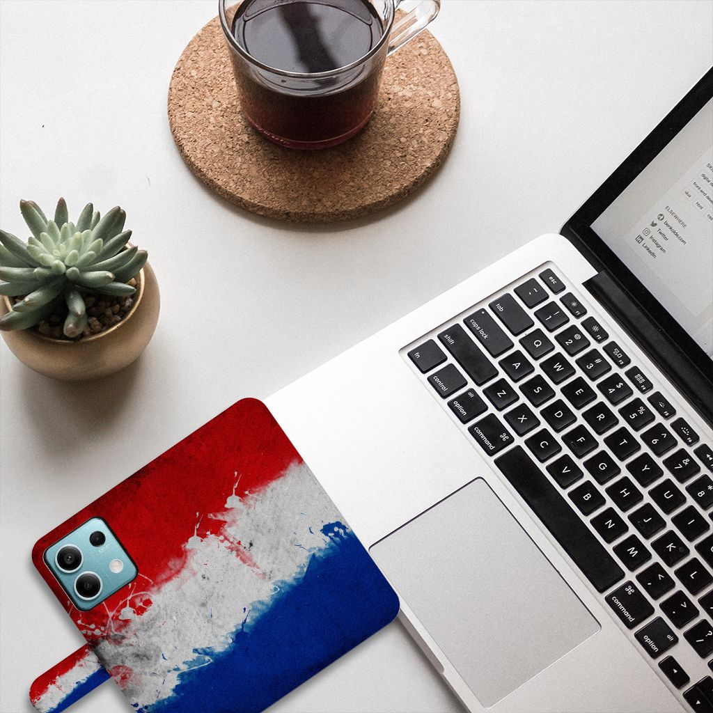 Xiaomi Redmi Note 13 5G Bookstyle Case Nederland met artistiek design van de Nederlandse vlag op bureau met laptop.