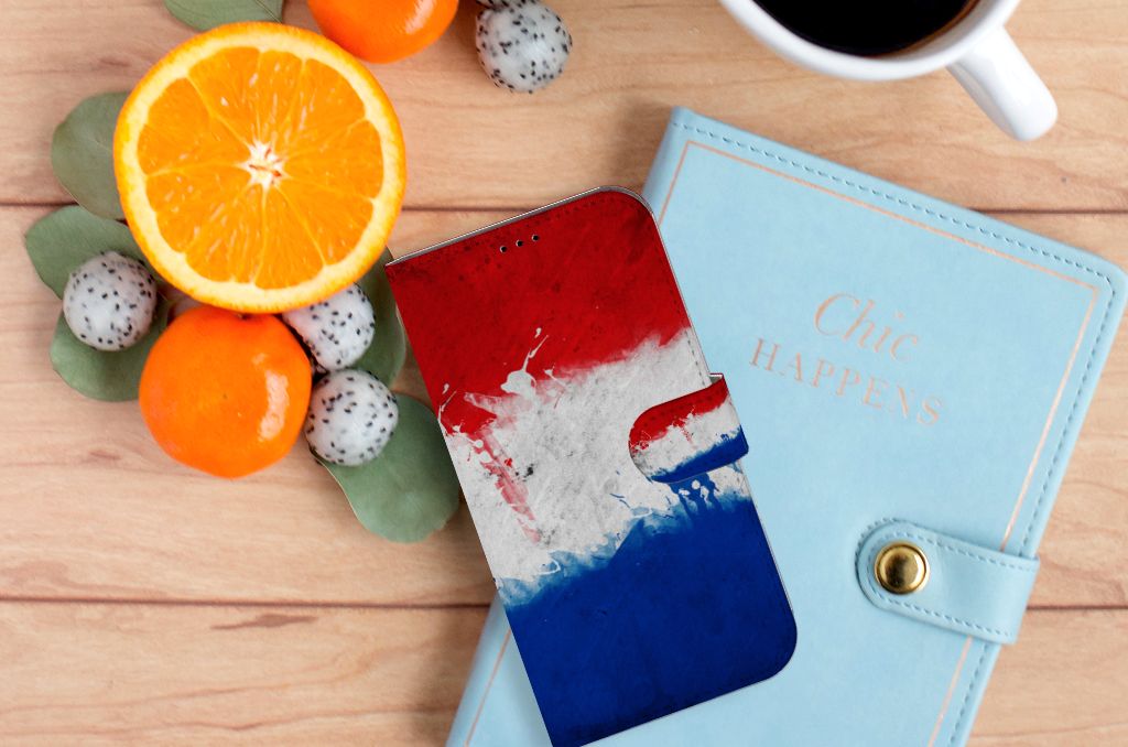 iPhone 14 Plus Bookstyle Case Nederland met Nederlandse vlag op een houten tafel met fruit en een notitieboek.
