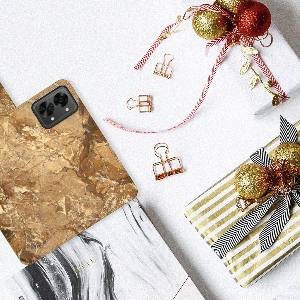 OnePlus Nord 2T Bookcase Marmer Creme op een tafel met geschenken en decoraties.