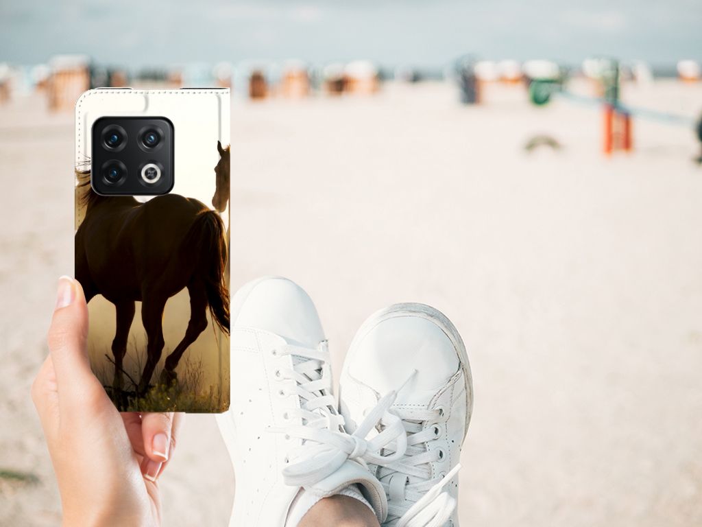 OnePlus 10 Pro Hoesje maken Design Cowboy met paardenprint, handig vastgehouden op het strand.