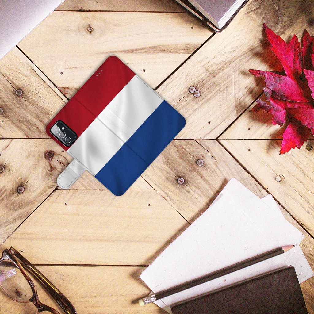 Samsung Galaxy M52 Bookstyle Case Nederlandse Vlag op een houten tafel met schriften en brillen