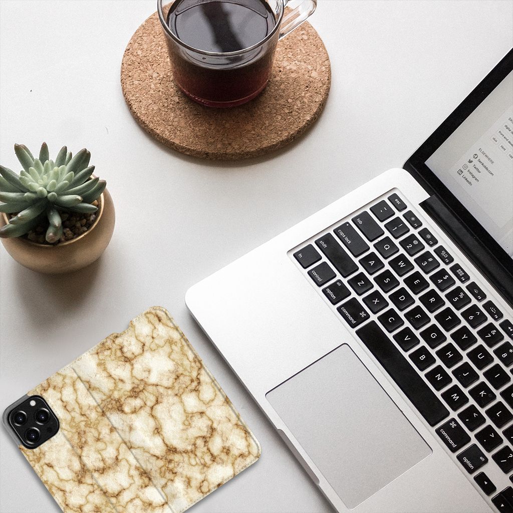 iPhone 13 Pro Max Standcase Marmer Goud met een stijlvolle gouden marmerlook op een bureau met laptop en drankje.