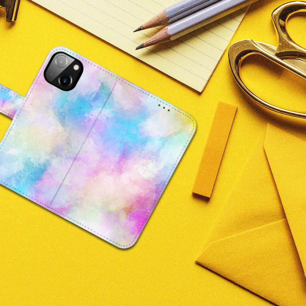 Hoesje Apple iPhone 14 Watercolor Light op een gele achtergrond met pennen en scharen.