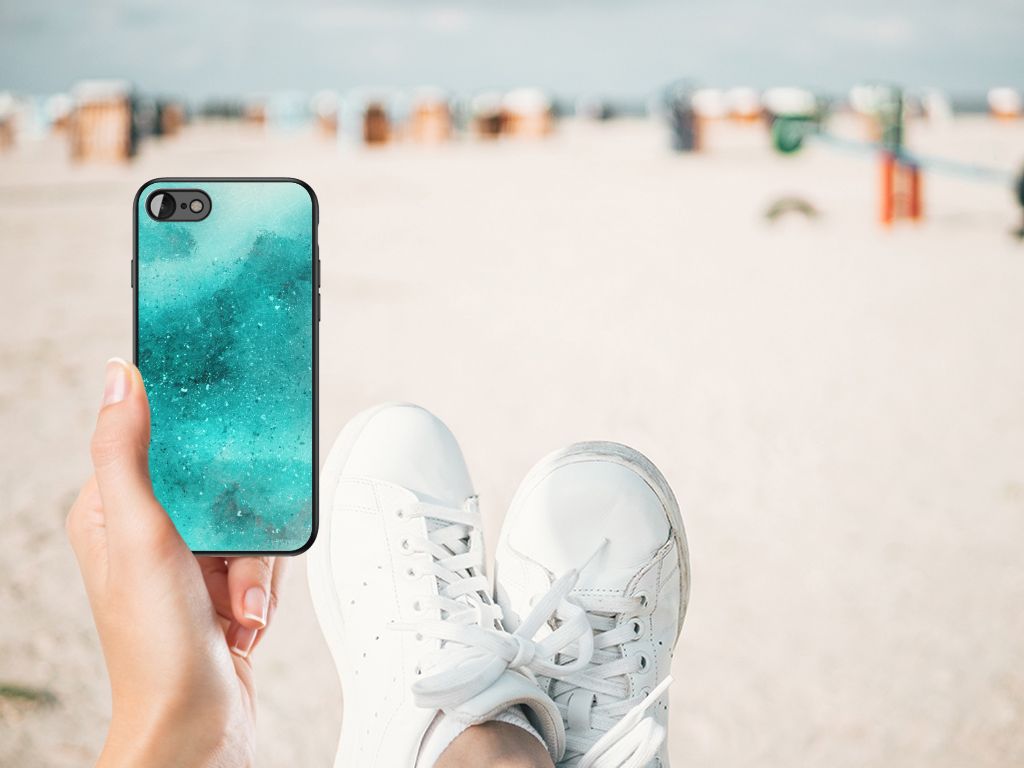 Kleurrijke Telefoonhoesje iPhone SE 2022 | SE 2020 | 7/8 Painting Blue op een strand met sneakers.