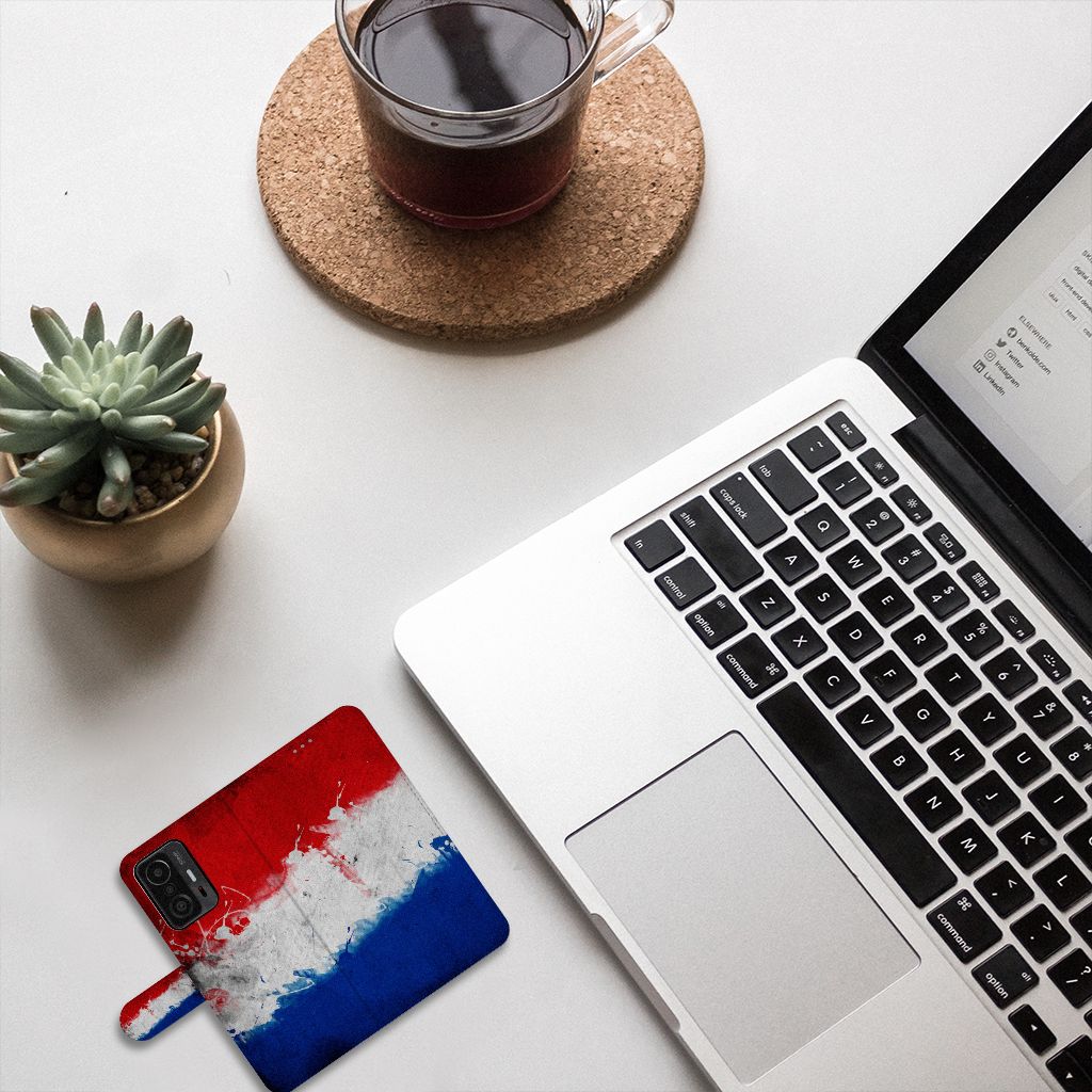 Xiaomi 11T | 11T Pro Bookstyle Case Nederland met design van de Nederlandse vlag op een bureau met laptop en planten.