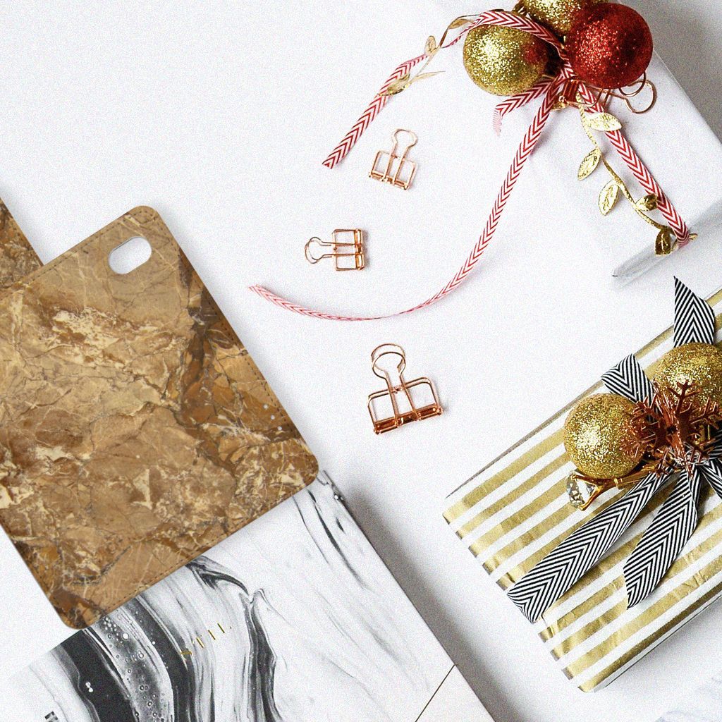 Alcatel 1B (2020) Bookcase Marmer Creme op een tafel met goudkleurige ornamenten en cadeauverpakking.