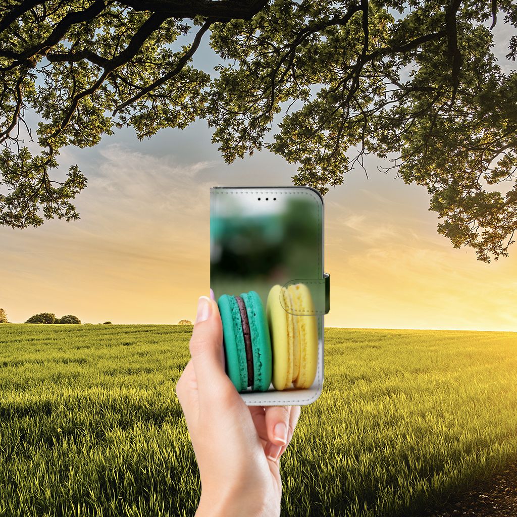 Apple iPhone 13 Book Cover Macarons met kleurrijke macarons in de hand voor een zonsondergang op het platteland.