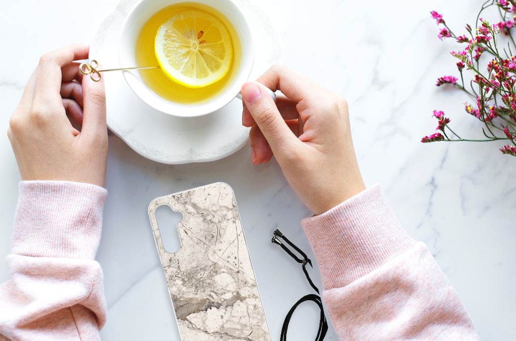Samsung Galaxy A14 5G Anti-Shock Hoesje Marmer Beige met hands die een kopje thee vasthoudt.