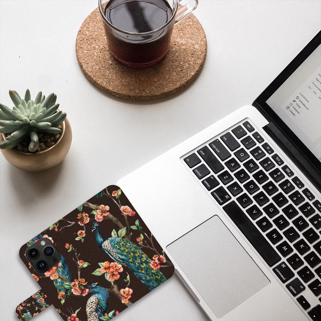 iPhone 15 Pro Telefoonhoesje met Pasjes Pauw met Bloemen op een bureautafel met laptop en planten.