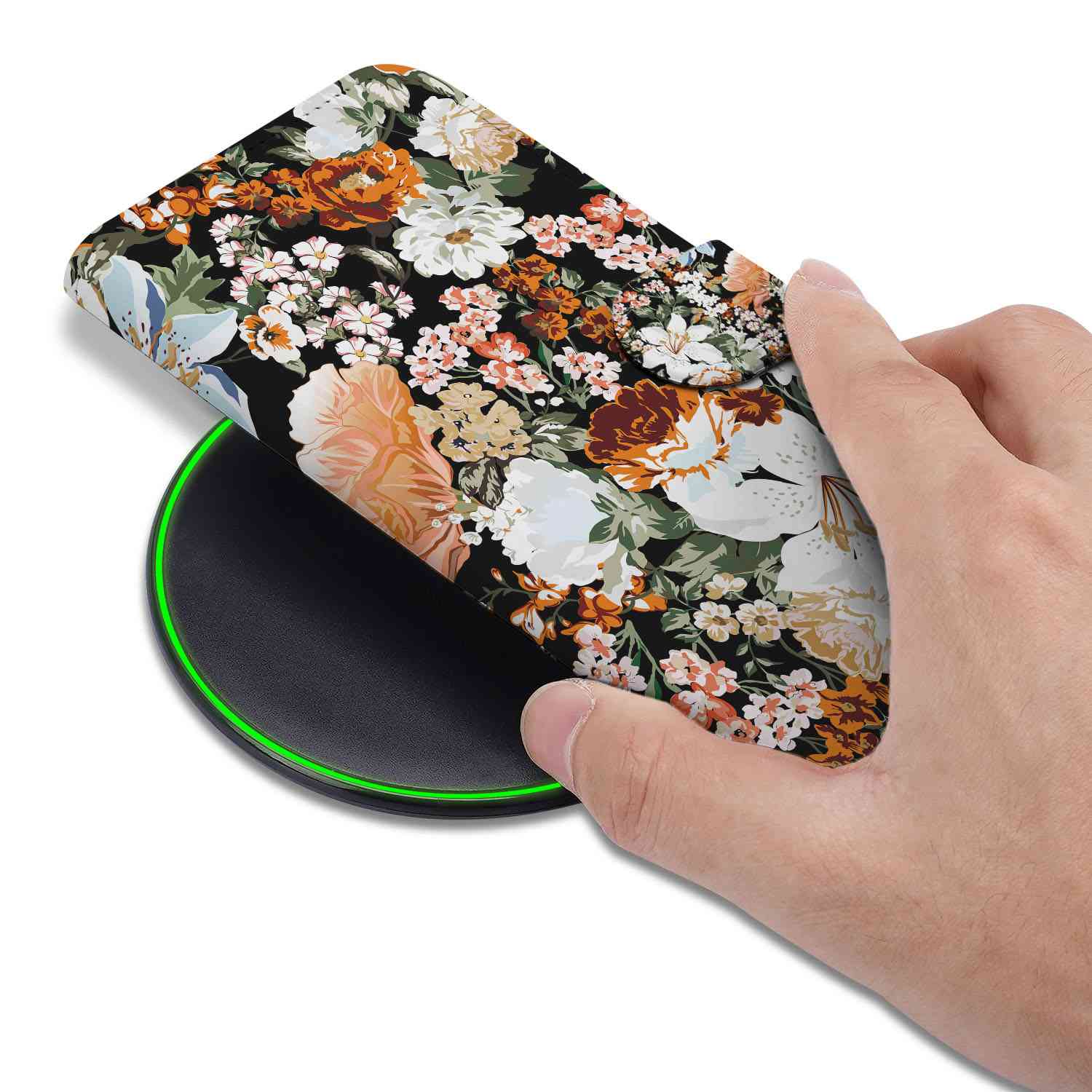 Hoesje voor iPhone 16e Dark Flowers met een hand dat het hoesje op een draadloze oplader plaatst.