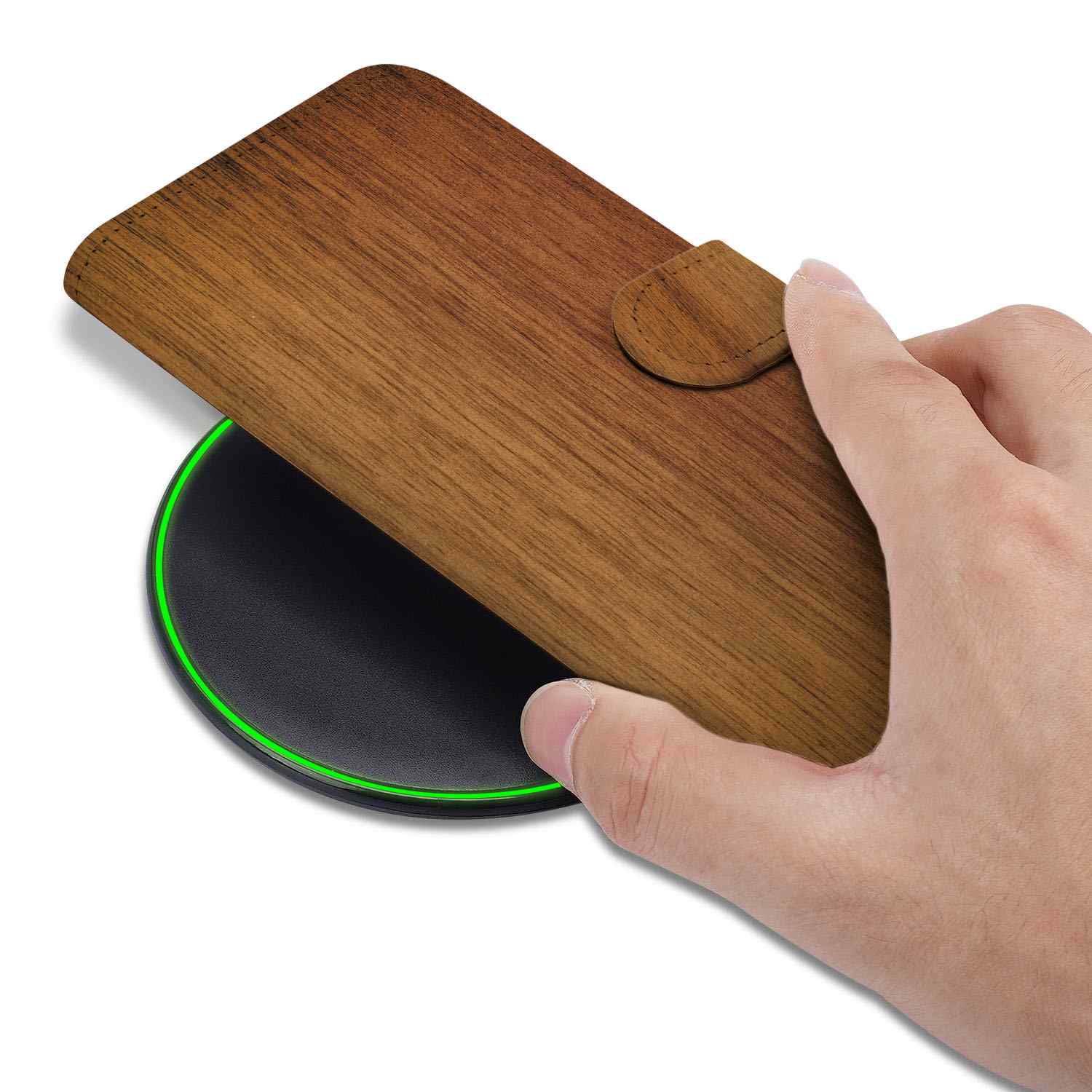 iPhone 16e Book Style Case Donker Hout op een draadloze oplader met hand die het hoesje vasthoudt.