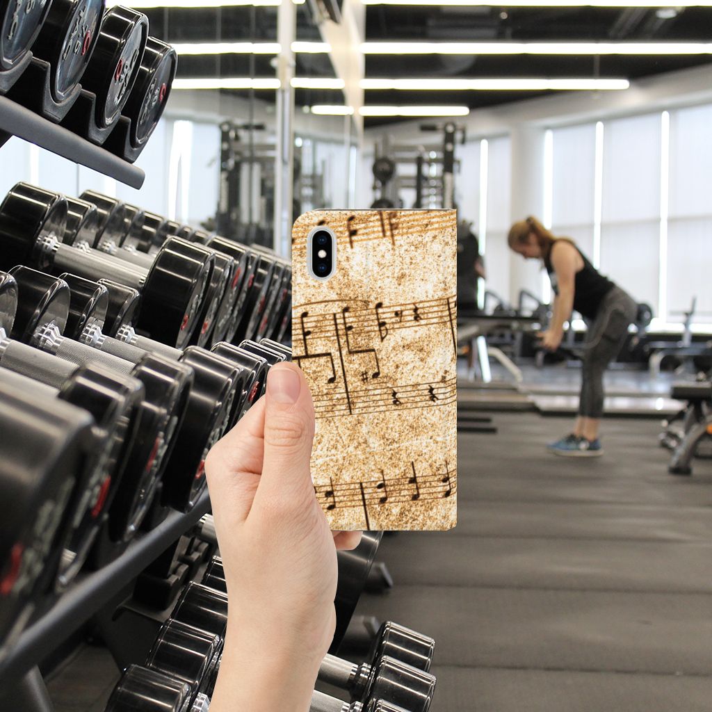 Apple iPhone Xs Max Stand Case Bladmuziek in de hand tijdens workout in sportschool met gewichten op de achtergrond