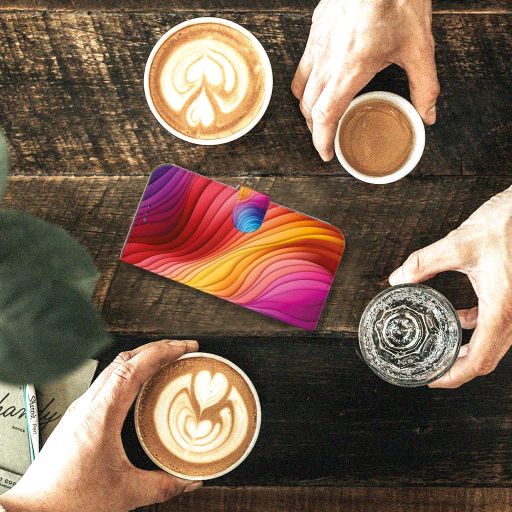 Book Case voor iPhone 14 Pro Max Regenboog met een kleurrijk ontwerp, omringd door koffie en water.