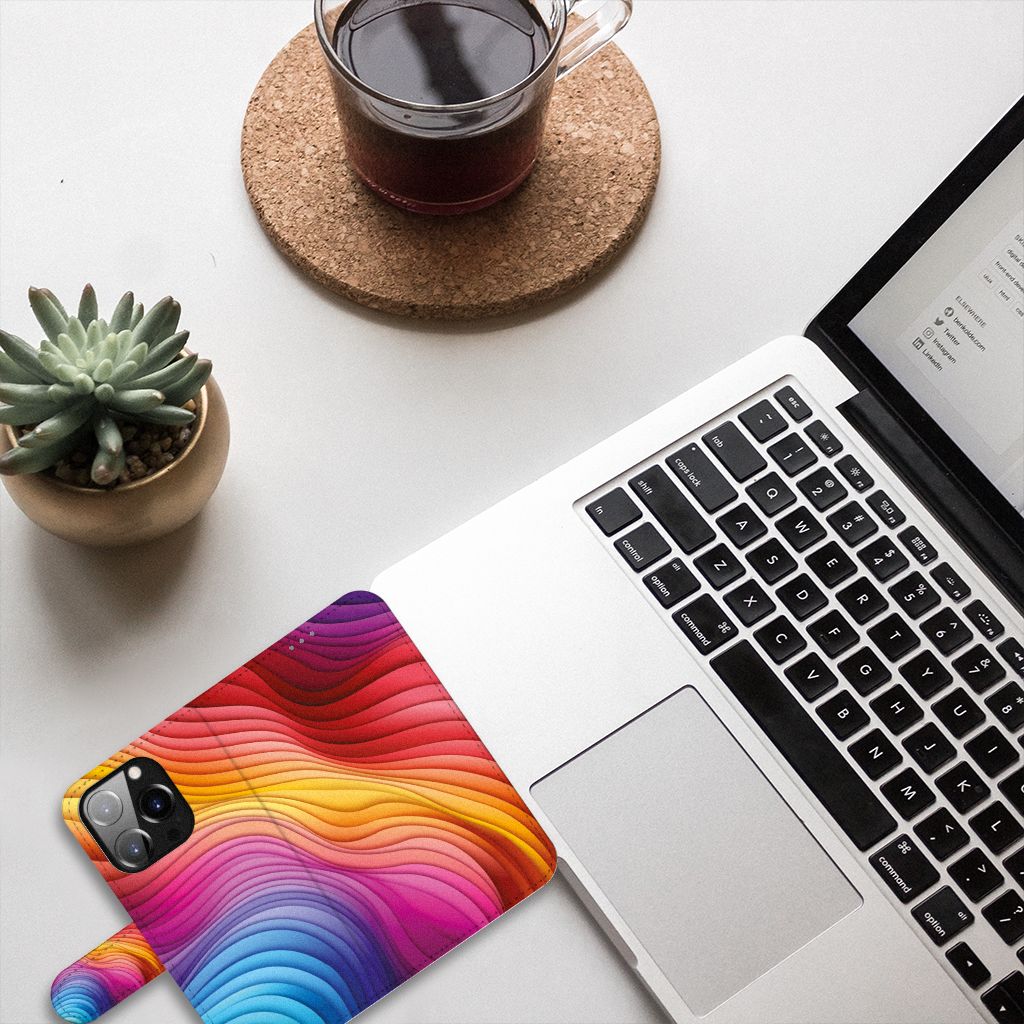 Book Case voor iPhone 14 Pro Regenboog met kleurrijk design op bureau naast laptop en plant 🌈