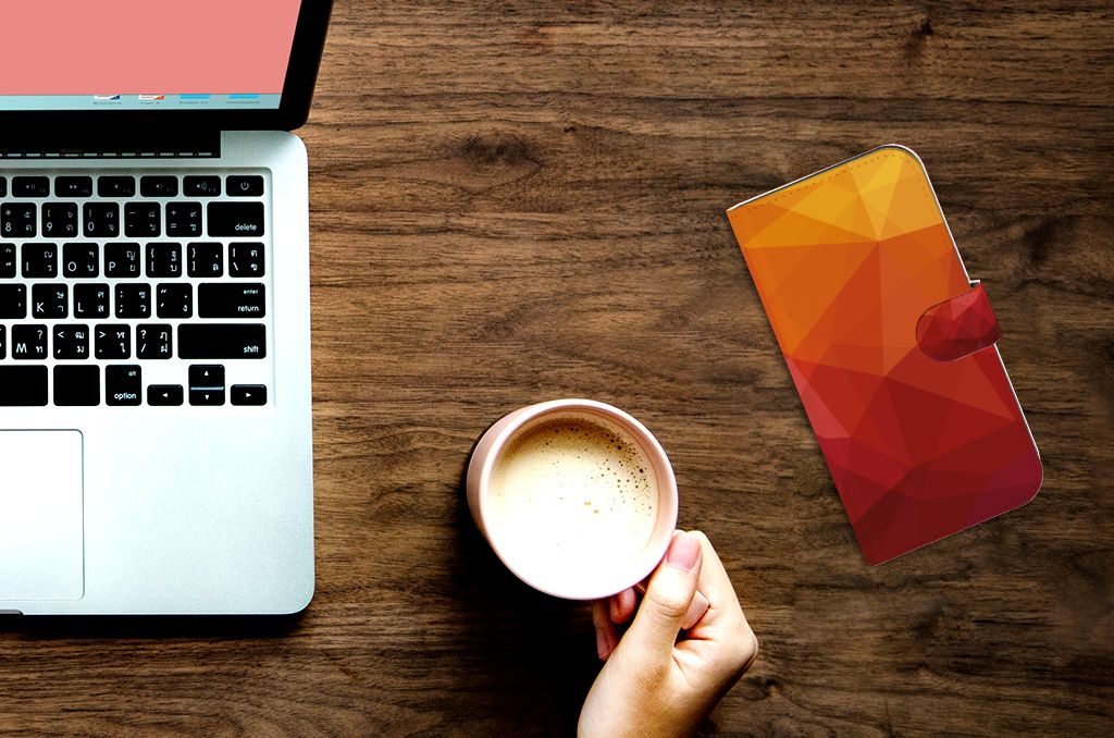 Book Case voor iPhone 15 Pro Max Polygon Red met een abstract design op een bureau, naast een kopje koffie.