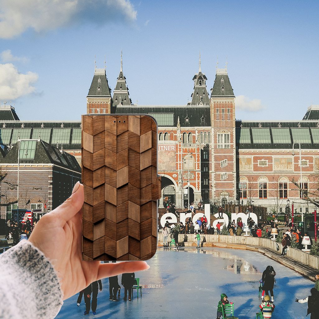 Hand holding a Book Style Case voor iPhone 13 Pro Max Wooden Cubes design in front of Amsterdam's Rijksmuseum.