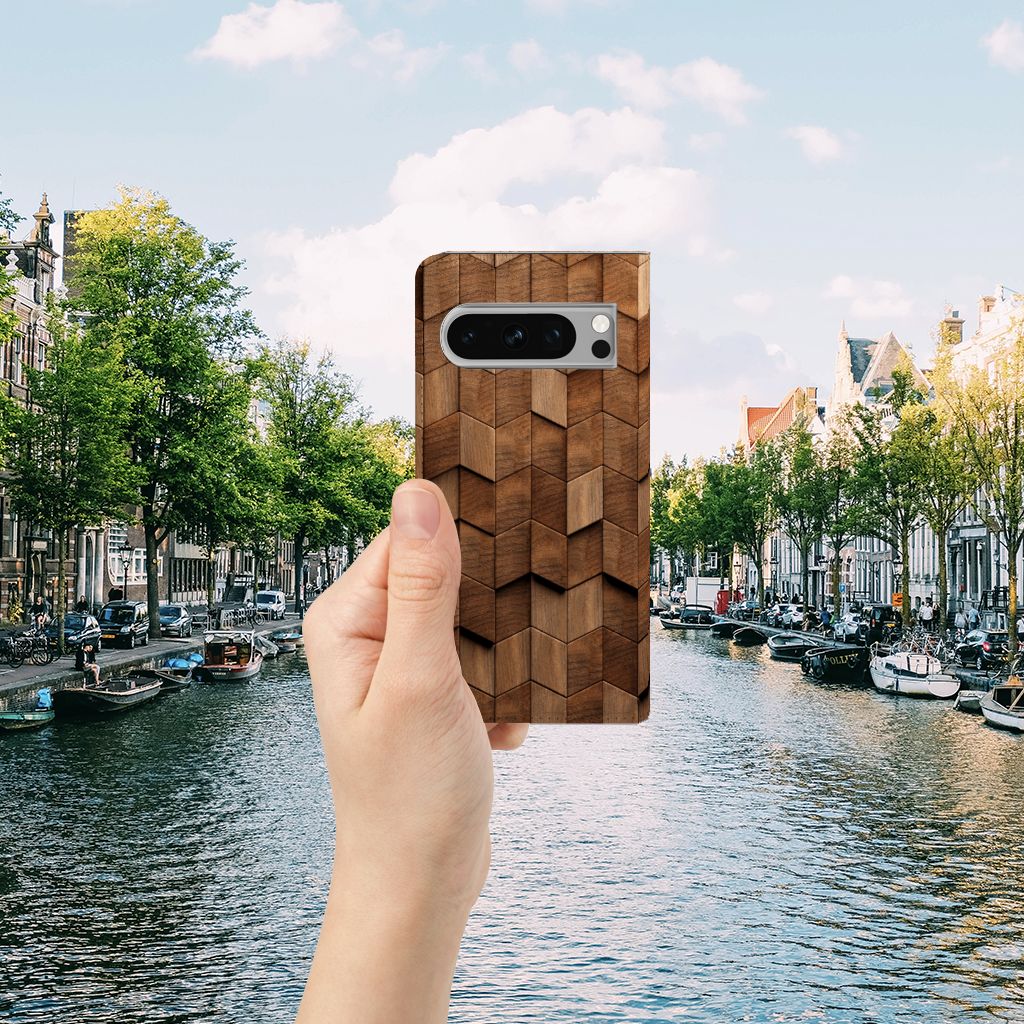Hand holding Book Wallet Case voor Google Pixel 8 Pro Wooden Cubes by a scenic canal, perfect cadeau voor stijl en bescherming.