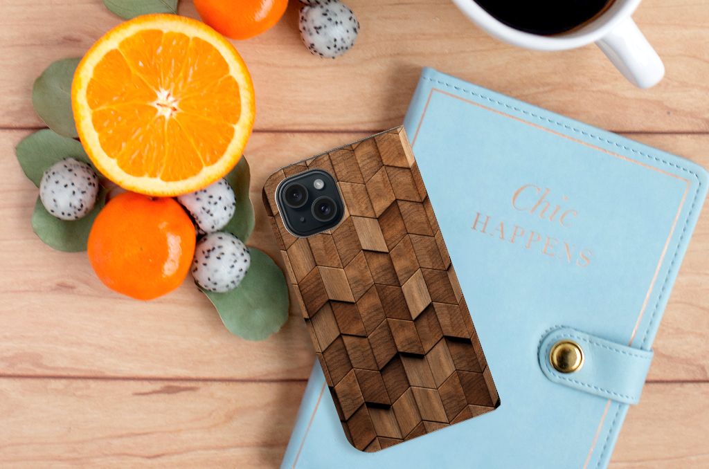 Book Wallet Case voor iPhone 15 Wooden Cubes op een houten tafel met fruit en een notitieboekje.