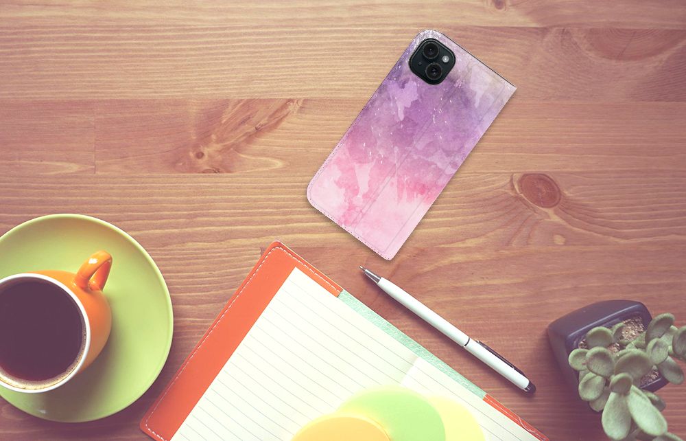 Bookcase iPhone 15 Plus Pink Purple Paint op een houten tafel met een kopje koffie en notitieboekje.