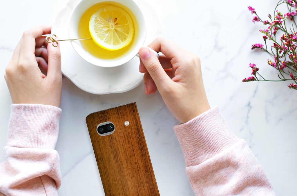 Google Pixel 7A Book Wallet Case Donker Hout hands kopje thee bovenaanzicht