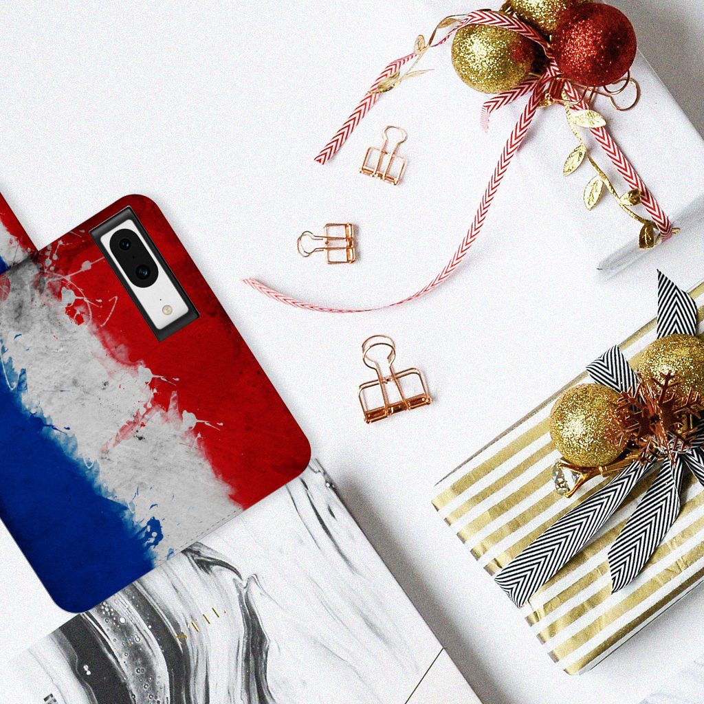 Google Pixel 8 Bookstyle Case Nederland met artistiek design van de Nederlandse vlag op een tafel met cadeaus.