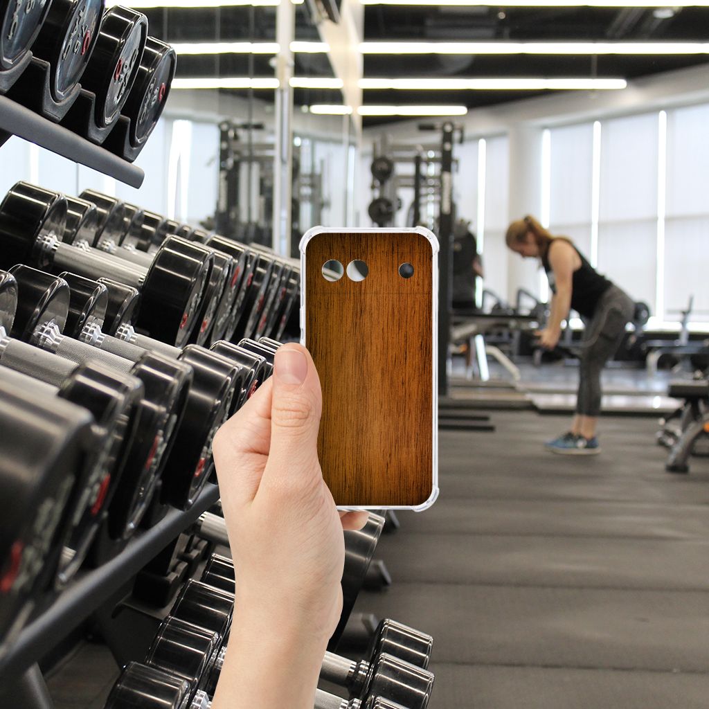 Google Pixel 8A Stevig Telefoonhoesje Donker Hout hand met hoesje in sportschool
