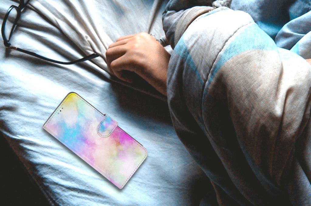 Hoesje OPPO A16/A16s/A54s Watercolor Light op een bed met een persoon die zich in een deken gewikkeld heeft.