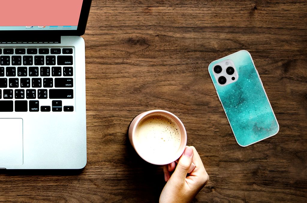 Hoesje maken iPhone 15 Pro Painting Blue naast laptop en kop koffie op houten tafel.