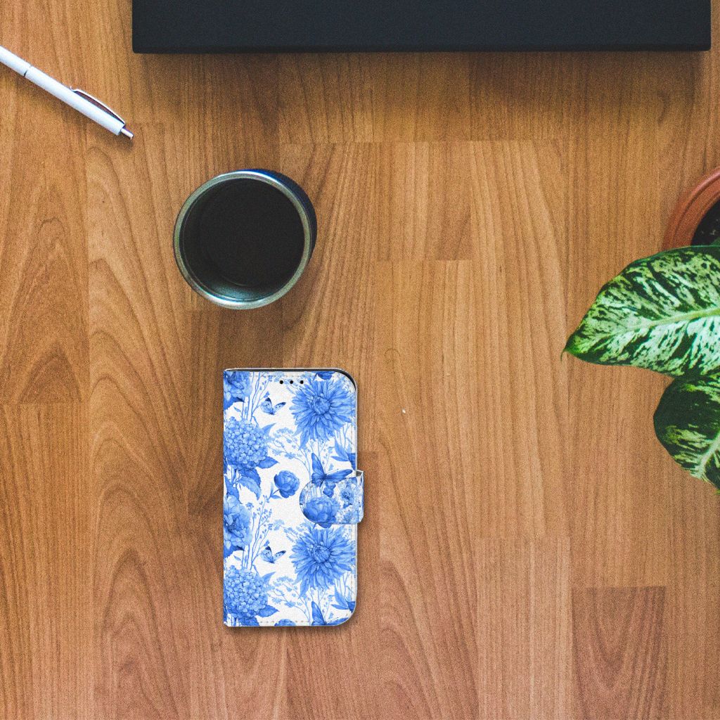 Hoesje voor iPhone 13 Mini Flowers Blue met een prachtig Delftsblauw bloemenontwerp op een houten tafel.