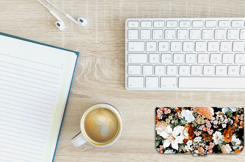 Hoesje voor iPhone 15 Plus Dark Flowers met bloemenprint, naast een koffie en notitieboek.