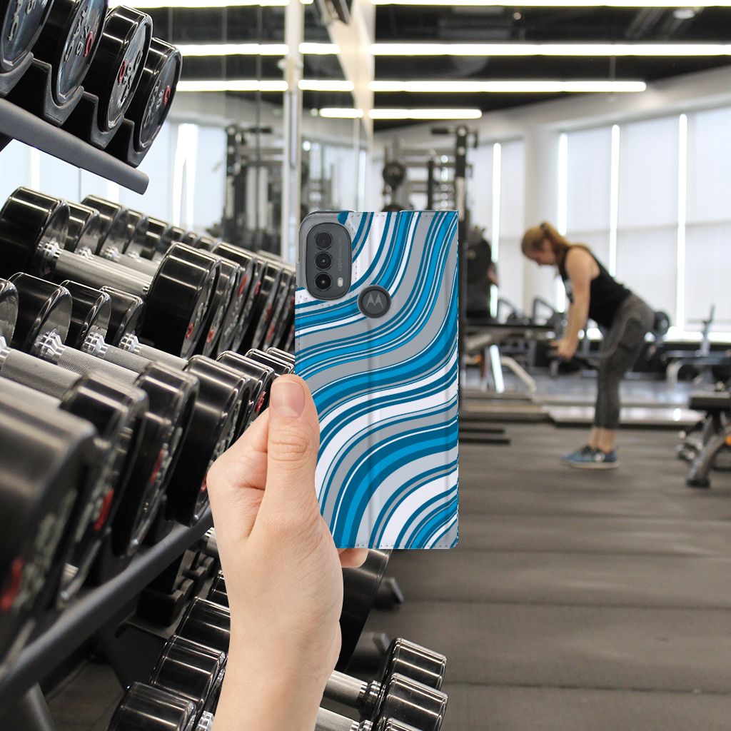 Motorola Moto E20 Hoesje met Magneet Waves Blue hand aan toestel gym achtergrond