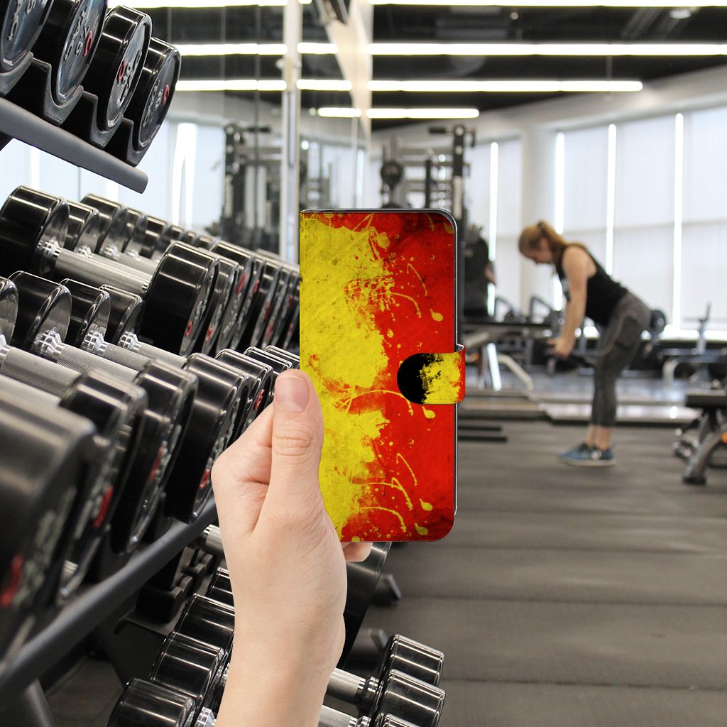 Motorola Moto G14 Bookstyle Case België in hand, kleurrijk design in sportschool met gewichten op de achtergrond.