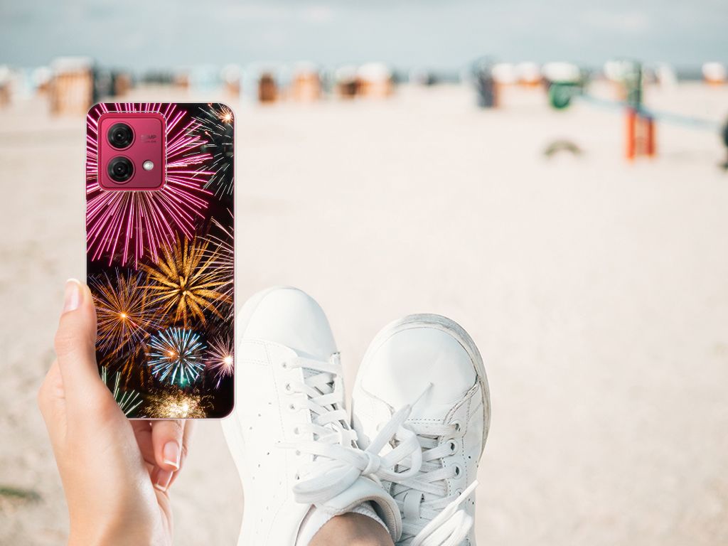 Hand holding Motorola Moto G84 Silicone Back Cover Vuurwerk with colorful fireworks design at the beach.