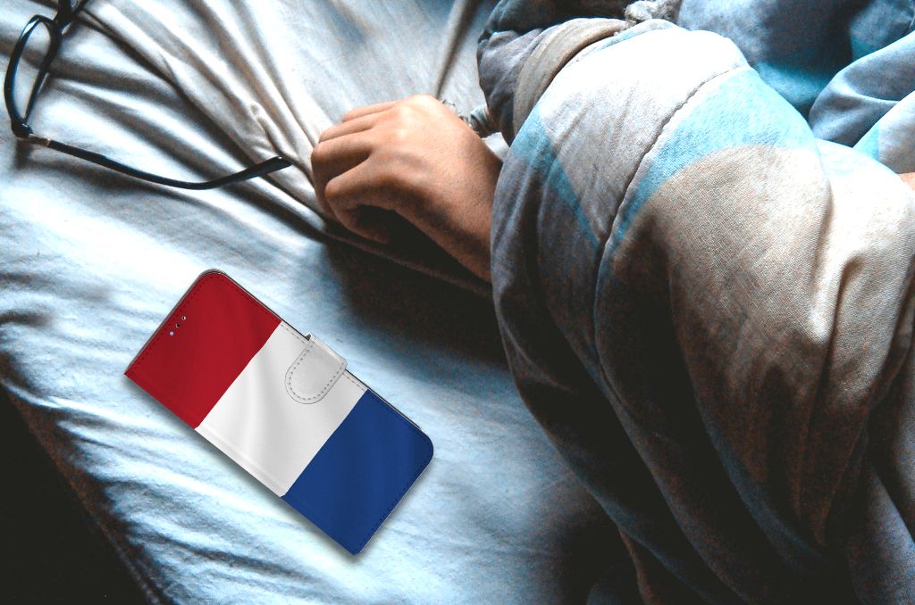 OPPO A16/A16s/A54s Bookstyle Case Nederlandse Vlag naast een hand op een bed.