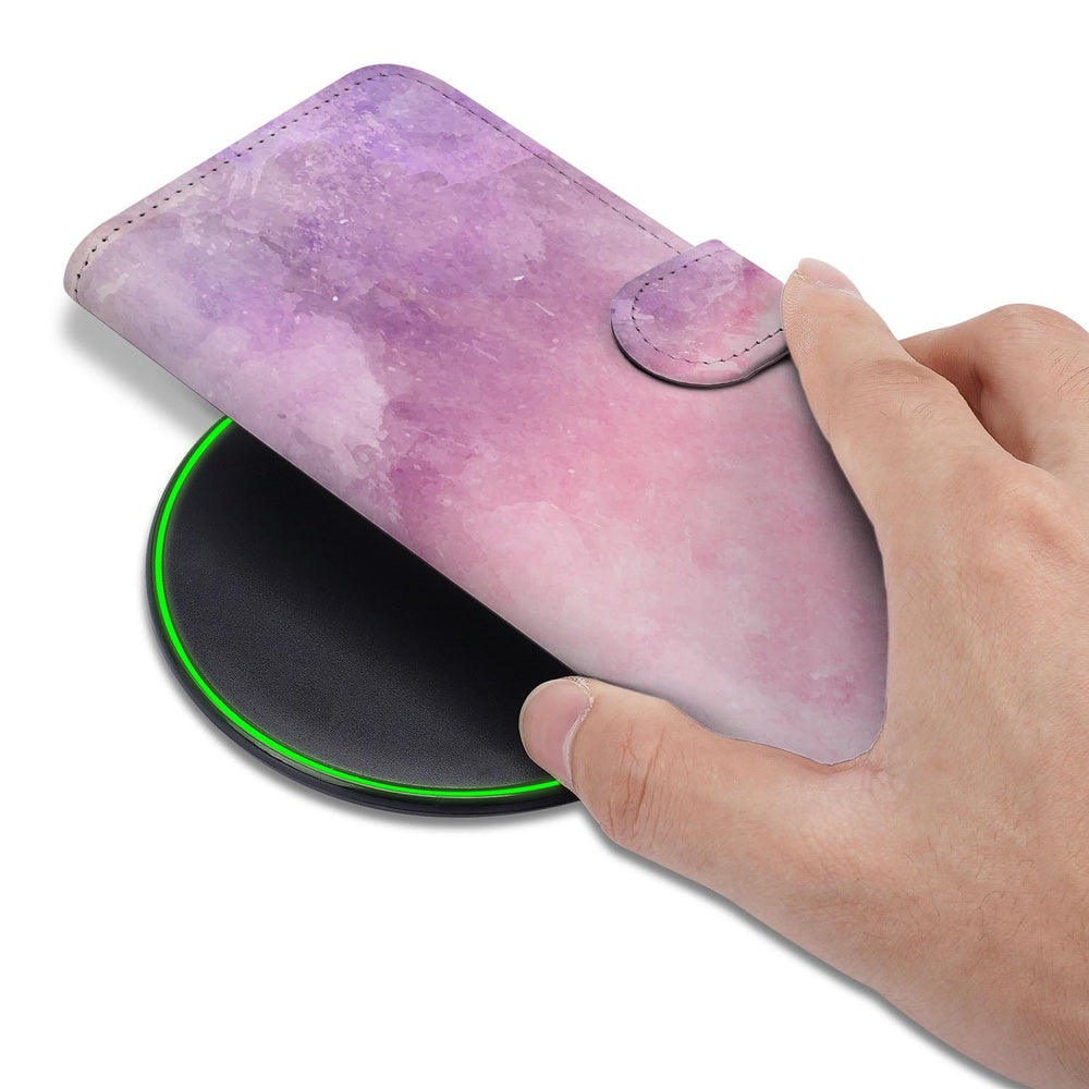 Samsung Galaxy S26 Plus Bookcase Hoesje Roze Paars Paint hand houdt hoesje boven draadloze oplader.