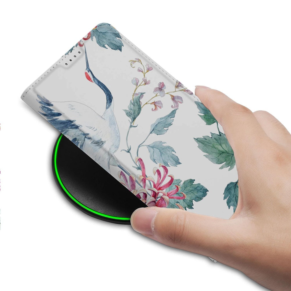 Samsung Galaxy S26 Plus Book Wallet Case Bird Flowers detail hand boven een draadloze oplader.