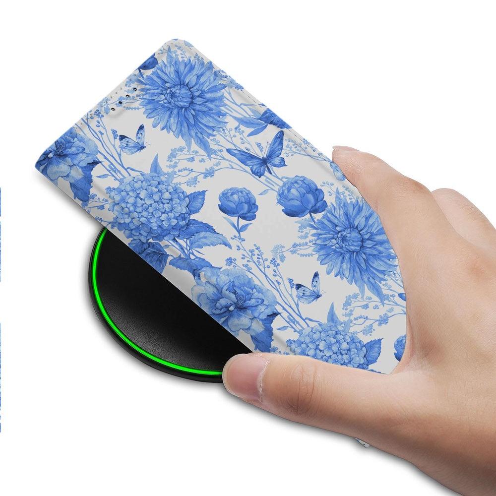 Samsung Galaxy S26 Ultra Book Case Flowers Blue Voorzijde met hand op draadloze oplader.