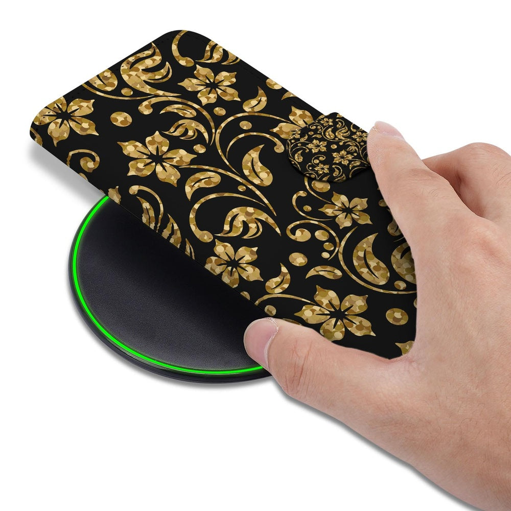 Samsung Galaxy S26 Hoesje Gouden Bloemen zwart met gouden bloemenontwerp boven draadloze oplader.