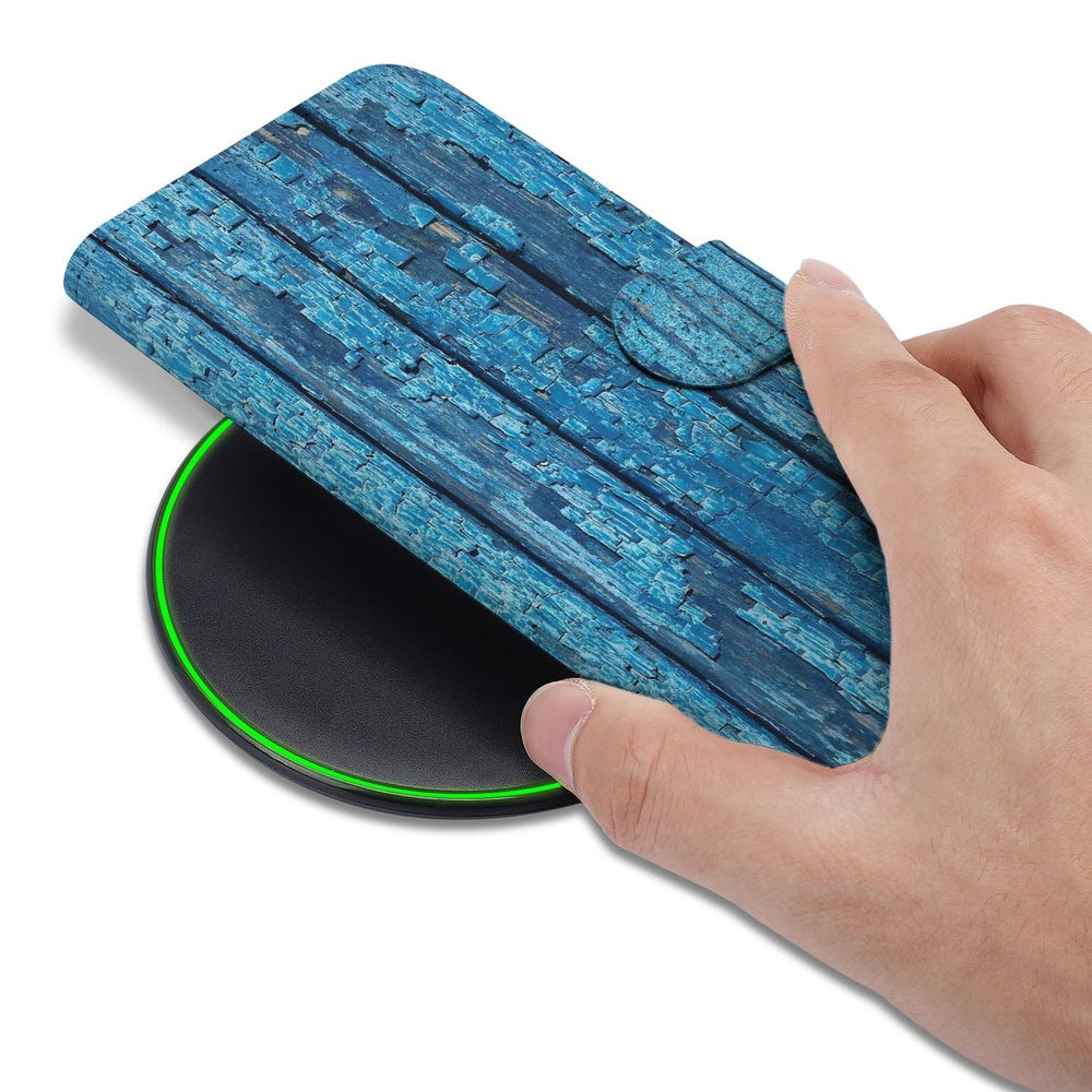 Samsung Galaxy S26 Book Case Hoesje Afgebladderd Blauw Hout hand boven ontwerp op draadloze oplader.