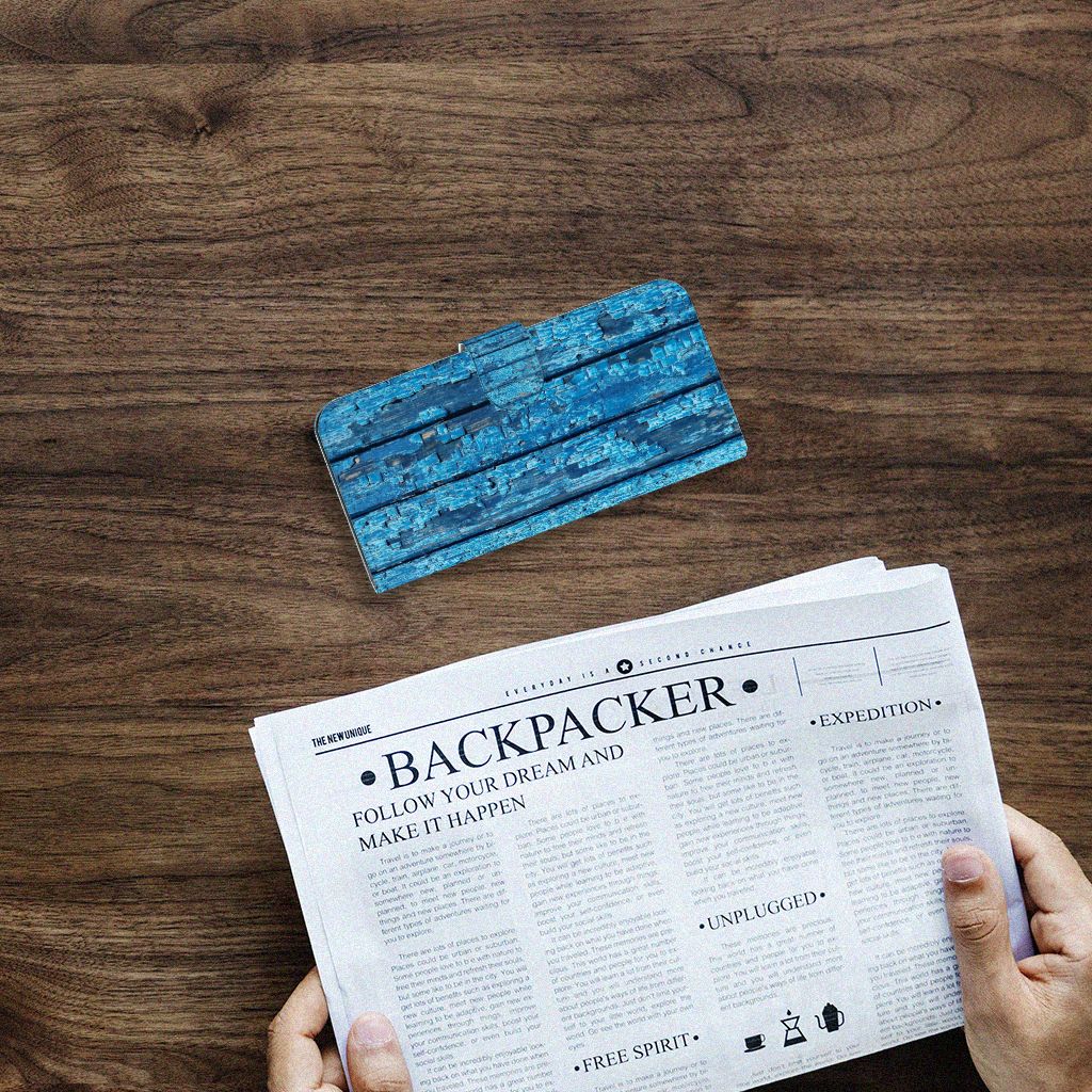 Samsung Galaxy A04e Book Style Case Wood Blue boekhoes met blauw afgebladderd hout bovenop een krant