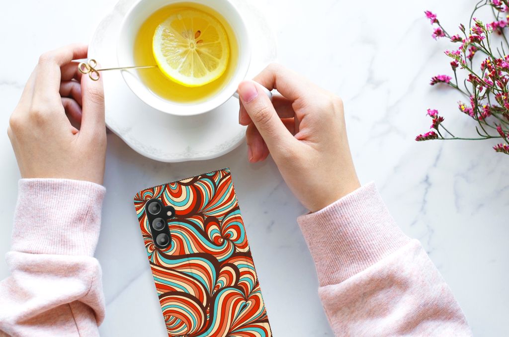 Samsung Galaxy A14 4G Bookcase Retro in artistic design with vibrant swirls, held with a hand beside a cup of tea.