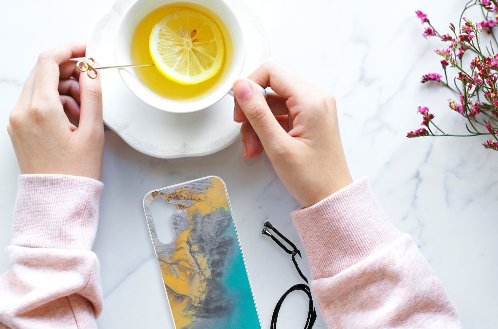 Samsung Galaxy A14 5G Anti-Shock Hoesje Marble Blue Gold naast een kopje thee met citroen.
