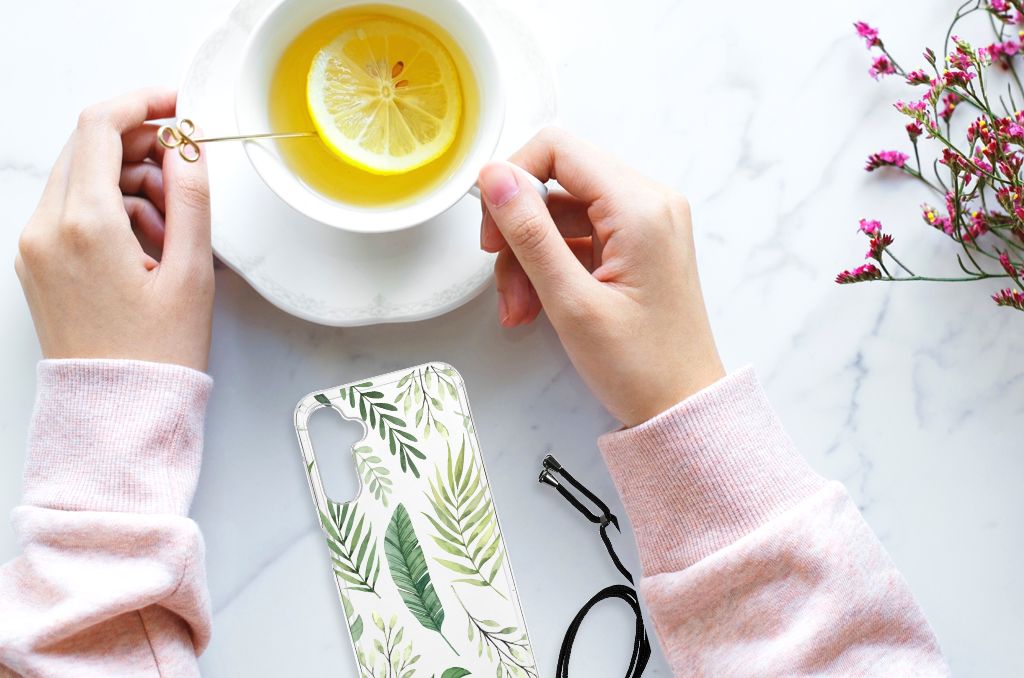 Samsung Galaxy A14 5G Case Leaves design displayed with a cup of lemon tea and hands on a marble surface.