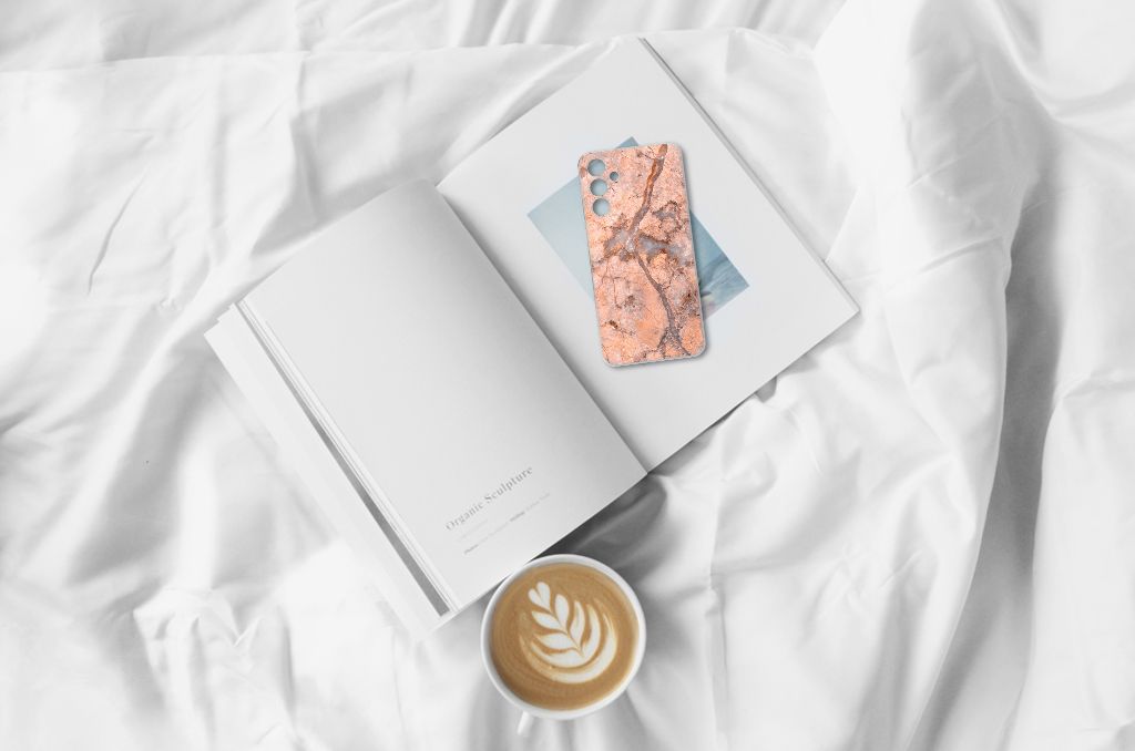 Samsung Galaxy A15 TPU Siliconen Hoesje Marmer Oranje op een bed met een boek en een kop koffie.