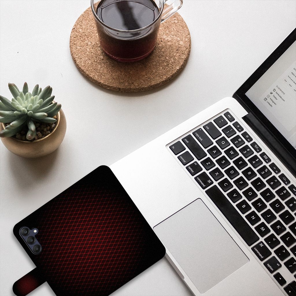 Samsung Galaxy A25 Telefoon Hoesje Geruit Rood op een bureau naast een laptop en een kopje koffie.